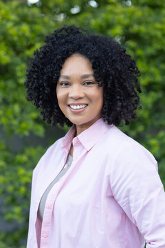 African American woman standing posing facing camera in park wearing pink shirt