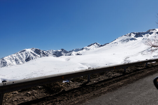 Andes mountains winter landscape along a winding road, a journey through snow-covered peaks under a clear blue sky, near la parva and santiago, chile