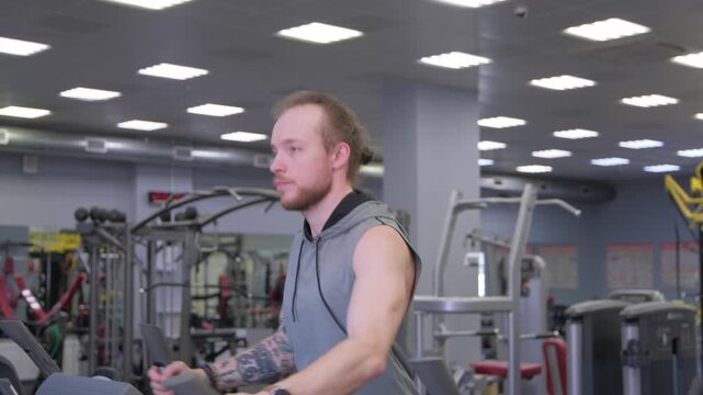 Man exercises on elliptical machine in gym during afternoon fitness session
