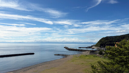 Fototapeta premium 青空と穏やかな海が広がる山あいの静かな海岸風景