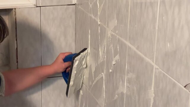 young woman applying grout in the shower, professional, DIY, user-generated content, close-up, 