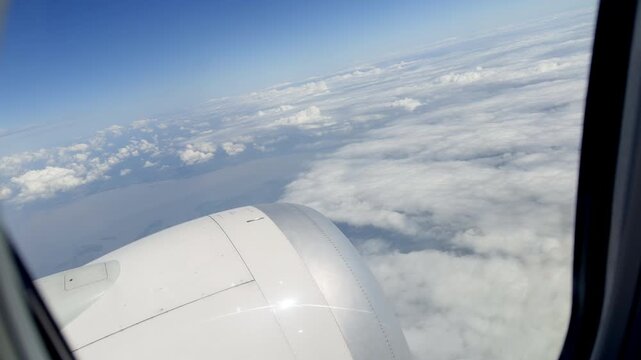 View of airplane engine and clouds through window