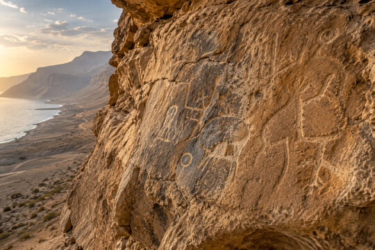 Ancient rock carvings weathered into desert cliff above coastal route