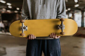 Skateboarder holding yellow skateboard in indoor skate park © Rawpixel.com