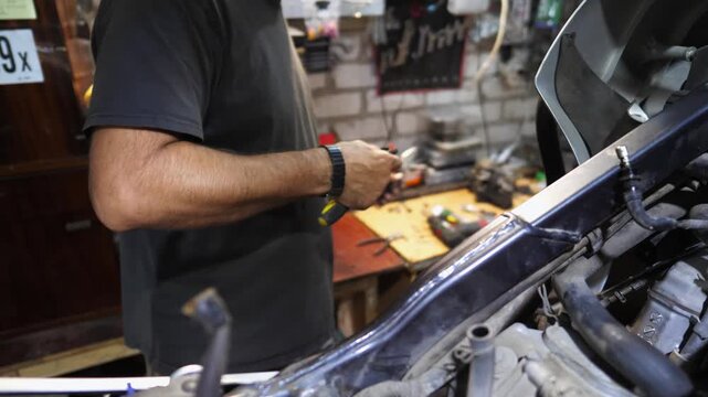 Male hands of mechanic repairing detail using tool at workplace. Arms of professional repairer fixing part of motorcycle at workshop. Adult repairman working at garage. Concept of maintenance service