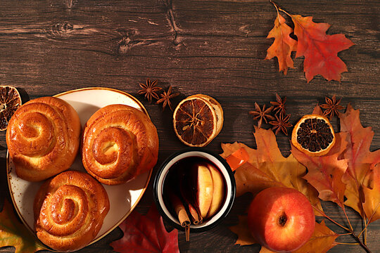 Cinnamon buns, hot mulled wine, fallen autumn leaves, star anise, ginger, and cinnamon on a wooden table, restaurant window banner, autumn welcome concept, cafe menu mockup,
