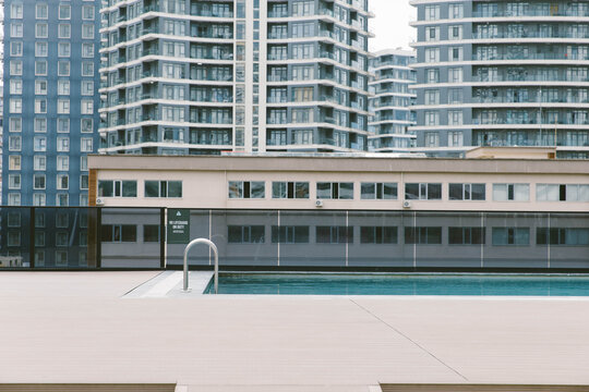 Empty outdoor swimming pool surrounded by modern residential apartment buildings, contemporary urban architecture and leisure area.