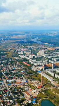Vertical video. Volgograd, Russia. Aerial panoramic sweep over the Krasnoarmeisky district, revealing dense Soviet-era panel housing, the Volga-Don Canal corridor, and the broad Volga River under an 