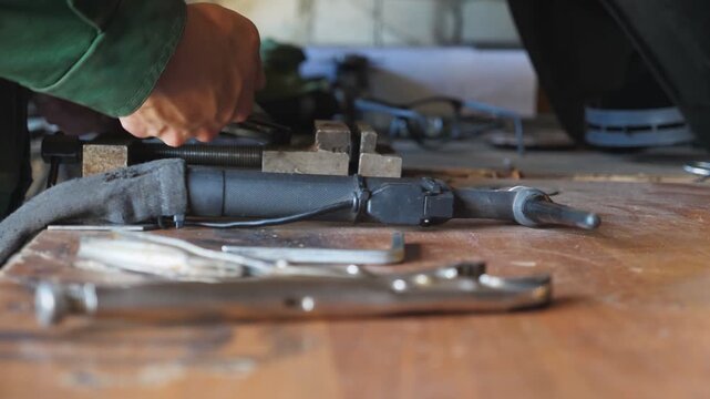 Male hands of repairman using pliers for fixing metal detail on table at workshop. Young mechanic working in garage. Concept of maintenance service. Close up Slow motion