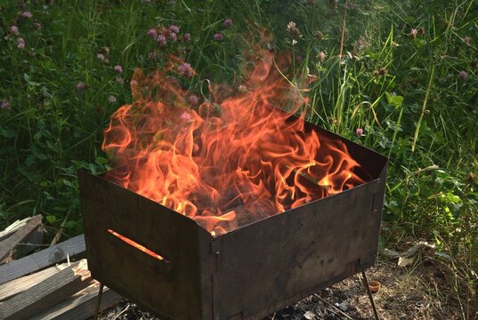 Metal brazier filled with burning wood logs and bright orange flames