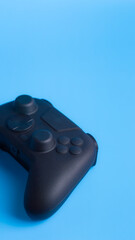 Vertical close up of black wireless gamepad on blue background with copy space. Perfect for social media gaming esports advertising.  © wibiwisnu