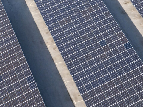 Drone view shows rows of solar panels set up in a parking area. The design supports electric mobility while promoting clean energy.