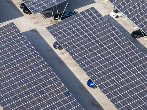 Aerial view of a solar parking area featuring solar panels and parked electric cars.