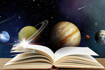 Fototapeta premium Open book on table against space with planets. Wonderful world of fantasy