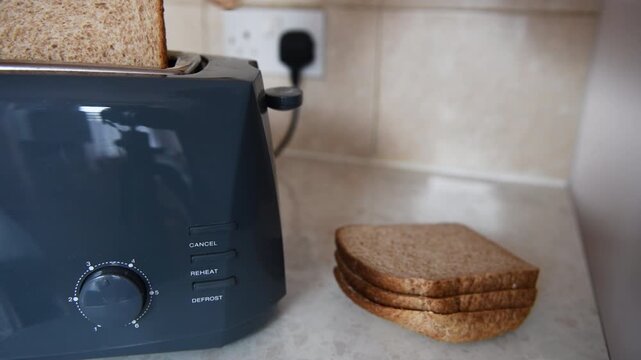A hand putting sliced bread into a toaster and pressing the on lever to make toasts. A domestic appliance, electricity use concept.