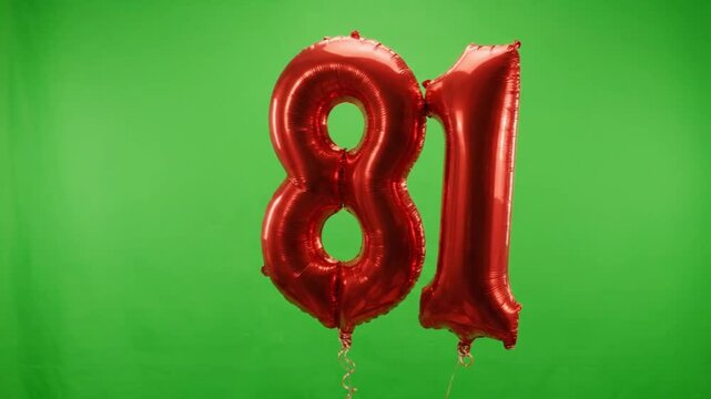 Red foil number 81 balloons on green screen background. Metallic eighty-one birthday balloons for anniversary celebration. Shiny red 81 helium balloon.