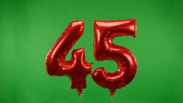 Red number 45 foil balloons on green screen background. Forty-five birthday celebration balloons. Anniversary party decoration with metallic red numbers.