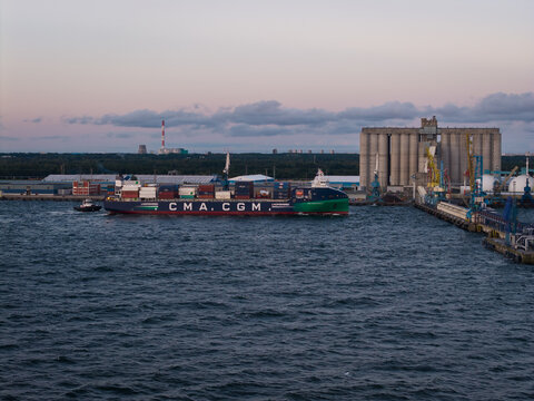 MUUGA, ESTONIA - SEPTEMBER 9, 2026: Aerial view of a CMA CGM container ship being guided by a tugboat towards the dock at Muuga Harbor port terminal.
