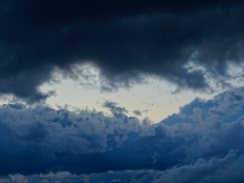 Dramatic dark storm clouds framing bright opening light in atmospheric sky with copy space
