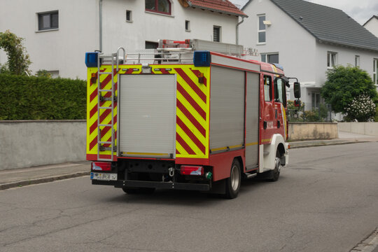 Stein, Germany - 18.09.2026. A municipal fire engine truck driving down a paved street past residential houses during a routine deployment or patrol in Stein, Bavaria, Germany.