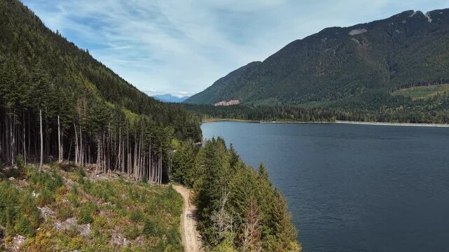 Aerial drone footage of a forest trail along a BC mountain lake