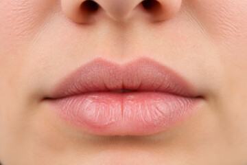 Obraz premium A close-up of a person's lips and nose is shown in a neutral setting.