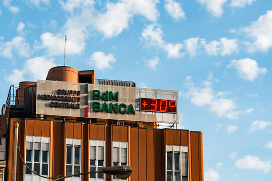 Bari, Italy - Aug 2, 2026: BdM Banca rooftop sign with a digital temperature display reading 30 degrees on a modern office building in Bari in Puglia, low angle view of the bank headquarters against 