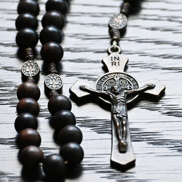 Rosary beads and cross on textured wood surface
