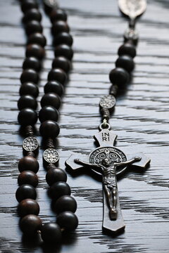 Dark Rosary Beads and Cross on Wooden Surface
