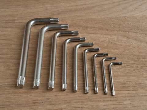 Set of Torx Keys on Wooden Background - A top-down view of a collection of L-shaped Torx screwdrivers arranged by size on a light wooden surface for hardware and DIY projects.