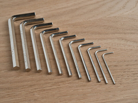 Set of Torx Keys on Wooden Background - A top-down view of a collection of L-shaped Torx screwdrivers arranged by size on a light wooden surface for hardware and DIY projects.