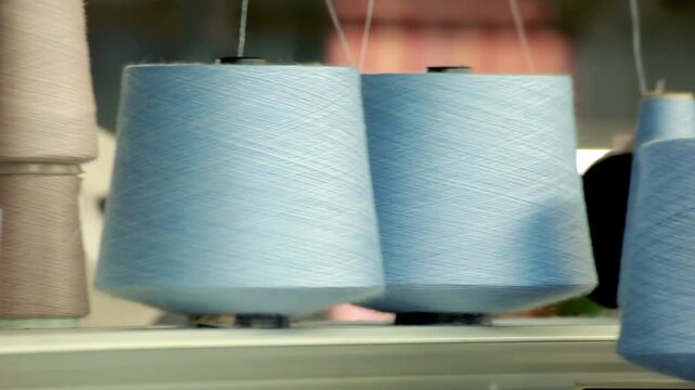 Colorful yarn cones knitting factory. Close up camera pan across thread spools.