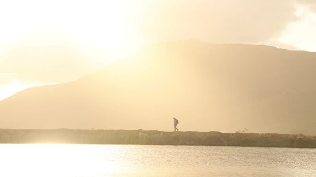 hiker in silhouette walking perimeter of pond at sunset,Stanford, South Africa