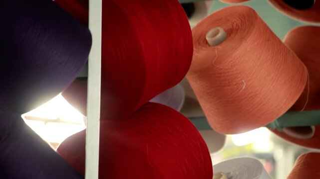 Thread bobbins rack textile factory. Close up red white yarn cones production.