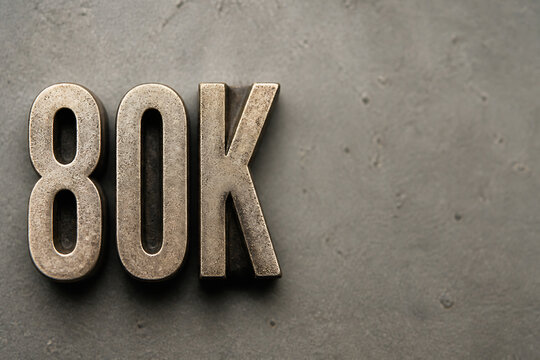 A metallic rendering of the text 80K is displayed on a dark, textured surface.