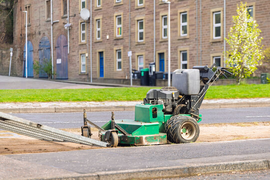 Commercial walk-behind mower parked on urban kerbside pavement