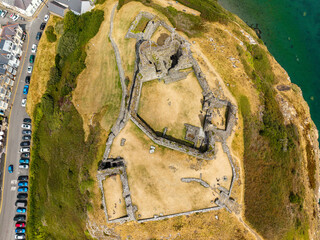 Aerial top down view of ruined stone castle walls on dry grassy hill, historic stronghold built on strategic headland, Wales, UK © whitcomberd