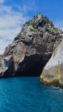 Fal&eacute;sias dram&aacute;ticas encontrando o mar azul calmo em um cen&aacute;rio de beleza natural intocada e c&eacute;u com nuves .