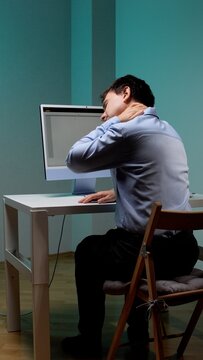 Man experiencing neck pain and discomfort while sitting at a desk, illustrating common ergonomic issues and fatigue from prolonged computer use in an office environment