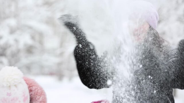 Mother and child are having fun outdoors in winter forest. A family plays in a nature park against a snow covered trees background. Healthy lifestyle and winter holidays concept.