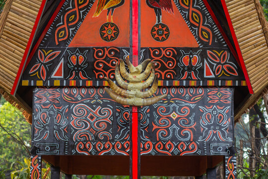 Traditional Indonesian Batak or Toraja wooden house facade decorated with intricate colorful folk carvings and buffalo horns