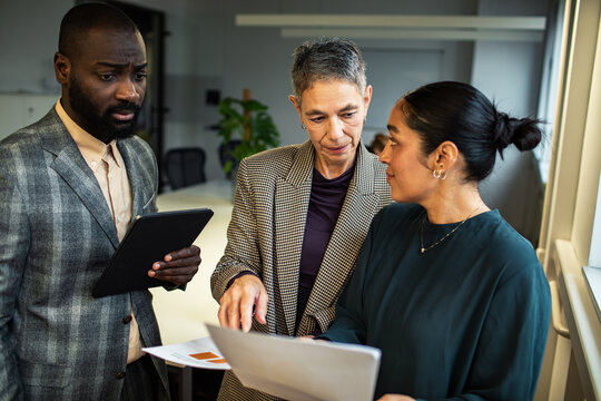 Three diverse business colleagues discussing strategy in modern office