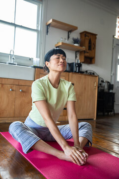 Woman practicing seated yoga stretch in home kitchen