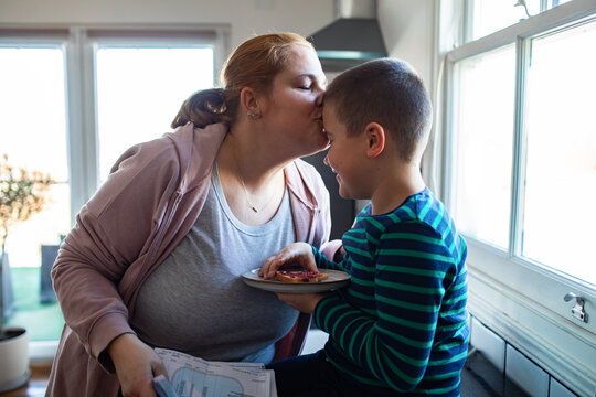Mother kissing son during breakfast in kitchen