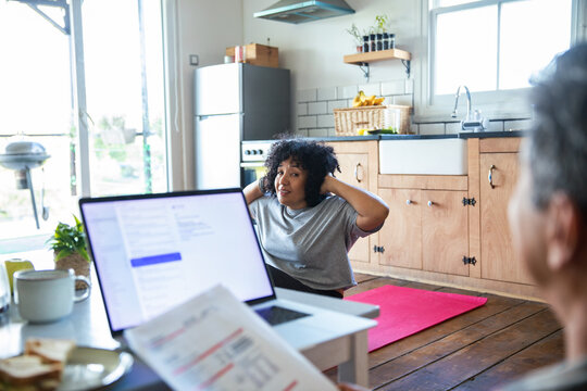 Woman doing sit-ups on yoga mat in home kitchen