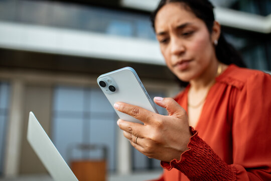 Businesswoman checking smartphone outside modern office