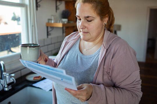 Concerned woman reading utility bill at home kitchen