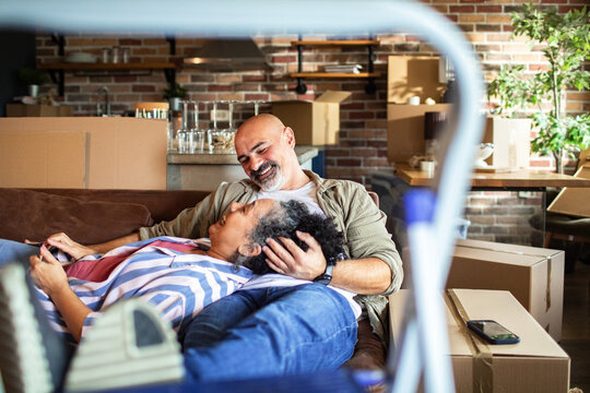 Mature couple relaxing on couch amid moving boxes at home