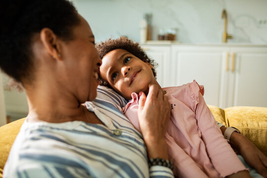 Mother and daughter cuddling on sofa at home