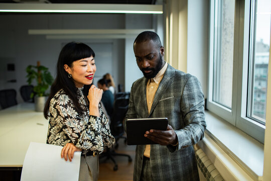 Two business colleagues reviewing a tablet by office window
